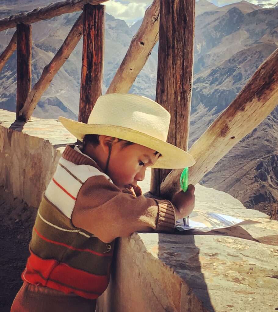 Bambino peruviano intento a disegnare le montagne
